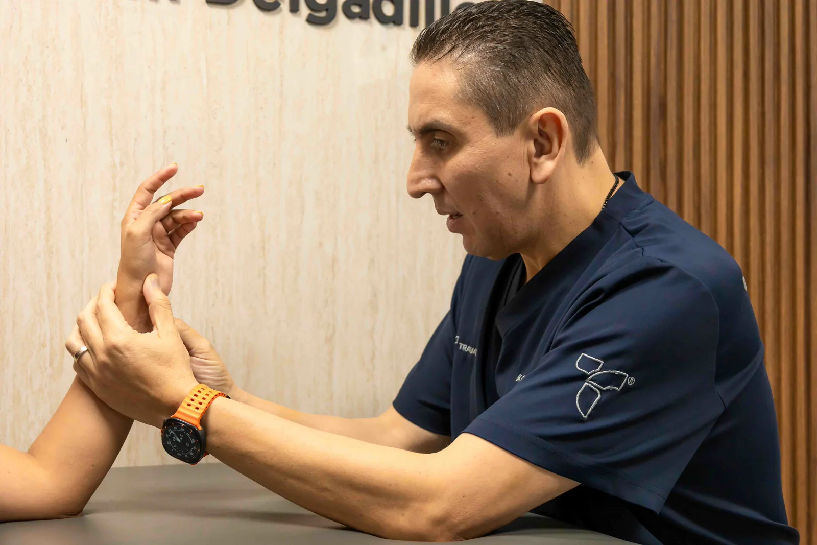 El Dr. Delgadillo explorando la muñeca de un paciente en consulta